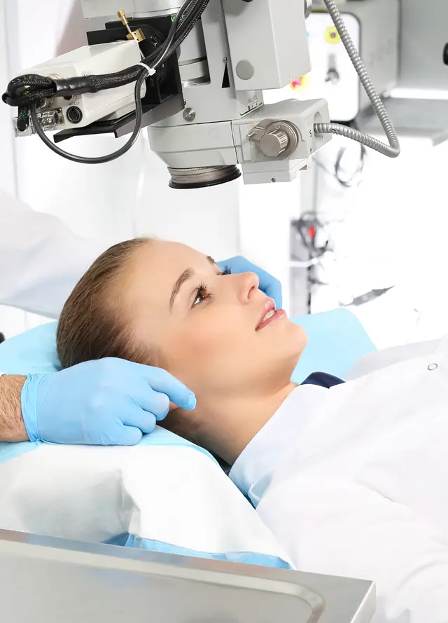 Patient lying comfortably beneath a surgical microscope before an eye procedure